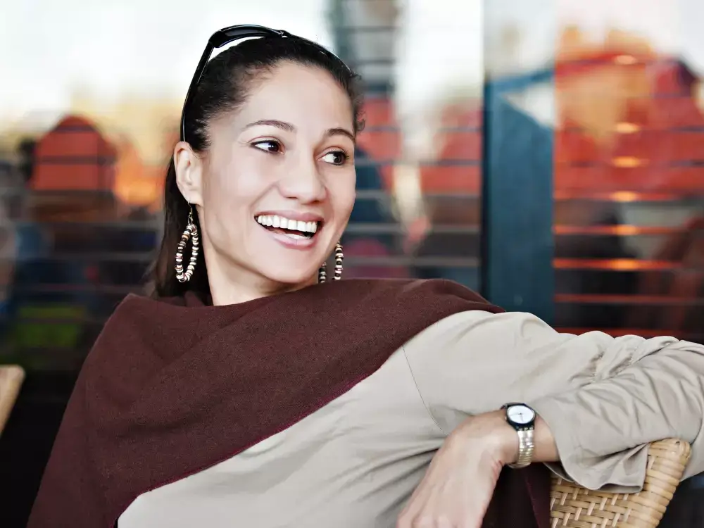 middle age mixed race woman sitting on a chair, laughing